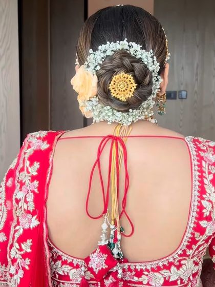 A detailed look at a bridal bun featuring a gajra of baby's breath and a central gold accessory. This combination of fresh flowers and traditional jewellery creates a rich and elegant finish.
