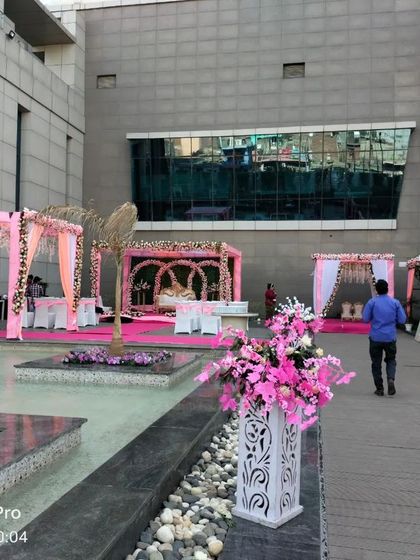 A poolside wedding setup at a modern venue. The pink-themed mandaps and stages are arranged around the water, creating a beautiful and contemporary layout.