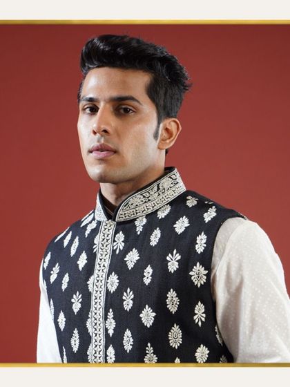 A close-up of a black raw silk Jawahar jacket with contrasting white embroidery. This distinctive and dressy piece is a versatile choice for any celebration.