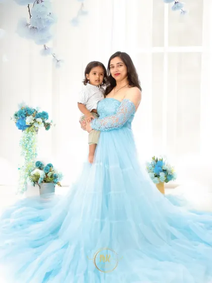 A mother holds her son in a tender embrace. Both are coordinated in blue and white for a serene and elegant portrait.