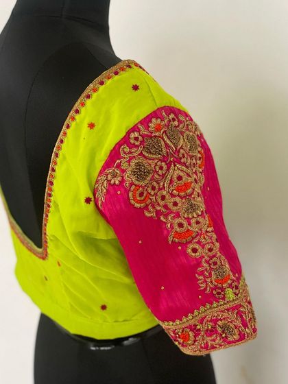 The side view of the neon green and pink blouse, showcasing the heavily embroidered contrast sleeve.