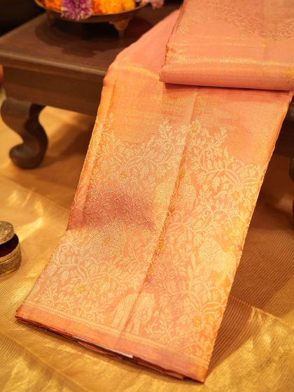 A delicate peach Kanjivaram with all-over silver zari brocade, a soft and elegant choice for a bride.