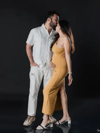 A classic and romantic pose. The forehead kiss is a timeless symbol of affection and care. The dark studio background makes this intimate moment feel even more personal.