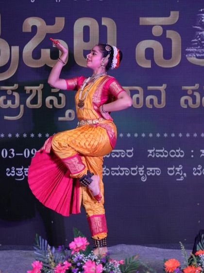 A full-stage shot of a classical dancer, capturing her mid-pose with the event backdrop visible. This shows my ability to cover the entire performance space.