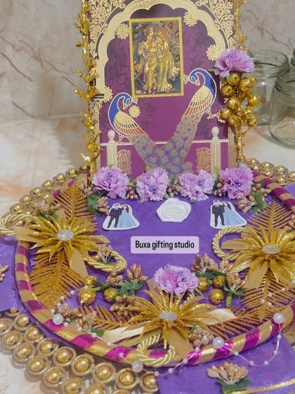 A detailed shot of the Radha Krishna engagement platter, showcasing the intricate gold and purple decorations.