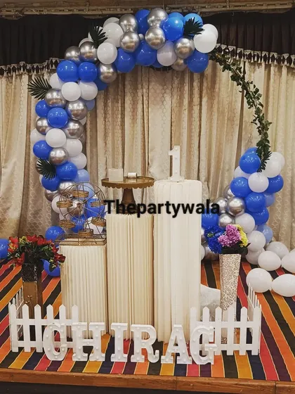 A simple and elegant ring decoration with blue, white, and silver balloons on a stage. The striped carpet adds an interesting pattern to the scene.