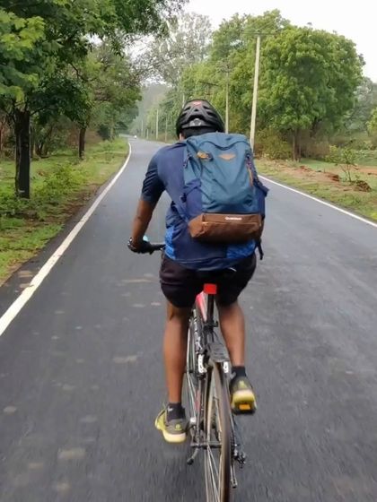 A rider cycles down a beautifully paved, tree-lined road. Our Hesaraghatta route is perfect for a smooth and scenic ride.