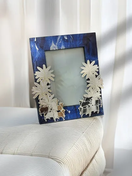 A striking blue patterned frame adorned with three-dimensional silver flowers. This piece is a whimsical and artistic way to display your favorite photos, adding personality to any surface.