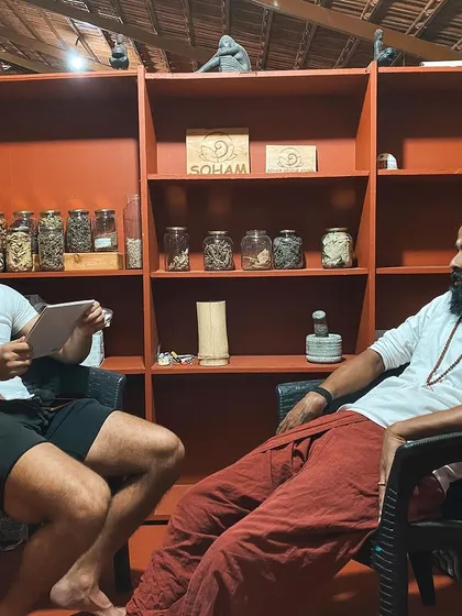 I sit with a student in our library, surrounded by jars of Ayurvedic herbs. Our discussions often bridge the connection between yoga, Ayurveda, and holistic health.