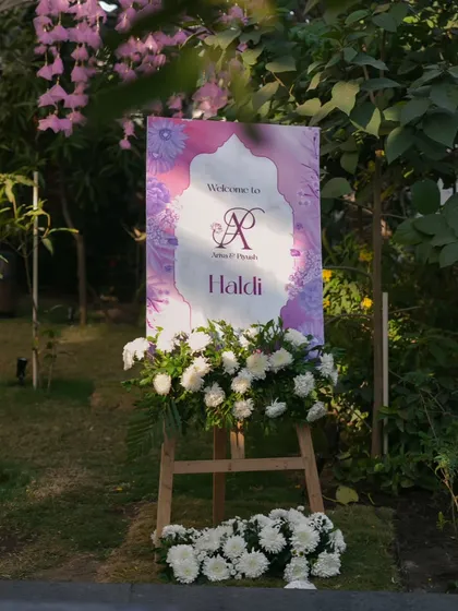 A personalized welcome sign for the Haldi ceremony, adorned with fresh white chrysanthemums. This is the first touchpoint for guests, and I ensure it reflects the event's elegant and personal nature.