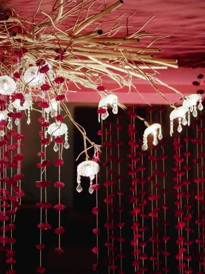 A detailed view of the custom-designed ceiling installation, where delicate glass lamps and crystal droplets emerge from a cluster of golden branches, intertwined with floral strings.