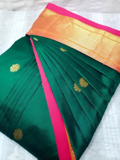 A deep green saree with a pink border and gold butis. The pleats are set, and the saree is ready to be draped in under five minutes.