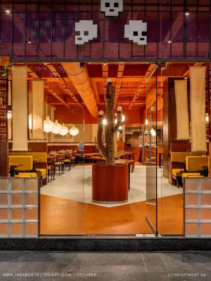 The entrance to Tres Amigos, a Mexican restaurant we designed, makes a bold first impression. We used a vibrant terracotta palette, glass blocks, and pixelated skull lighting to immediately immerse diners in a lively, modern interpretation of Mexican culture, setting the stage for the experience within.
