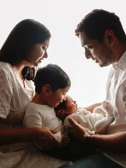 A beautiful high-key portrait of a family of four. The bright, airy light creates an angelic feel as they admire their newest little member.