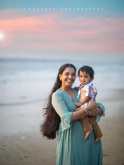 A mother and her son enjoying a beautiful sunset at the beach. The soft colors of the sky and her flowing hair create a dreamy, ethereal feel.