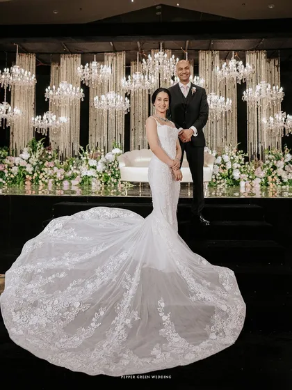 A stunning portrait of the bride and groom, with the bride's magnificent train spread out before them against a backdrop of glittering chandeliers. A moment of pure opulence and romance.