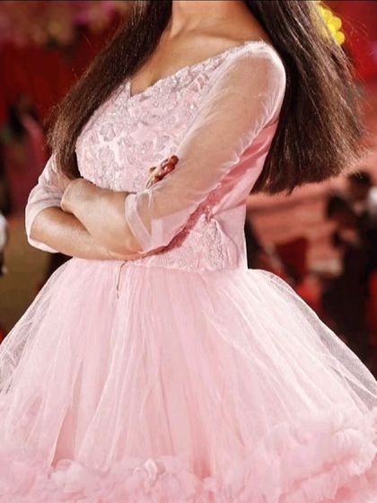 A closer look at the detailed bodice of the baby pink ball gown. The sheer sleeves and delicate beading add a touch of elegance.