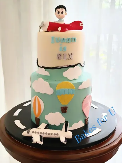 A two-tier aviation-themed cake with a fondant airplane, hot air balloons, and a runway. It's a perfect adventure cake for a 6th birthday.