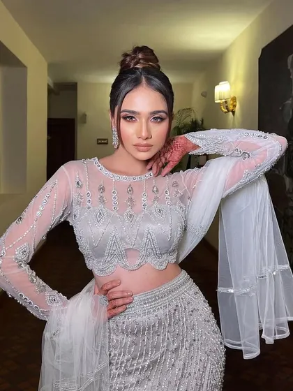A confident pose in the silver-grey ensemble. The styling highlights the intricate beadwork and the modern design of the outfit.