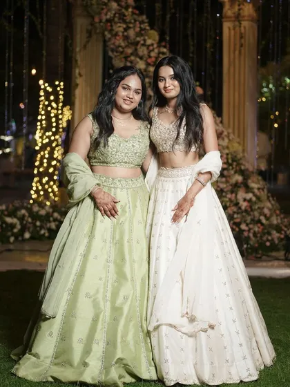 Another beautiful shot of our clients in their coordinated lehengas, standing before a stunning floral backdrop. Their smiles say it all.