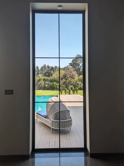 A framed view from inside looking out to the pool deck. We design windows not just as openings, but as picture frames that capture the beauty of the surrounding landscape, making it a part of the daily living experience.