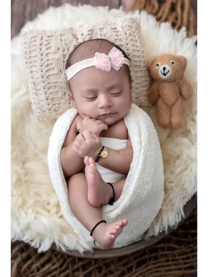 A perfect, peaceful portrait of a sleeping newborn. In my cozy Borivali studio, I create a safe and warm environment where your baby can rest comfortably, allowing me to capture these classic, angelic poses. This little one is swaddled and sleeping next to her tiny teddy bear companion.