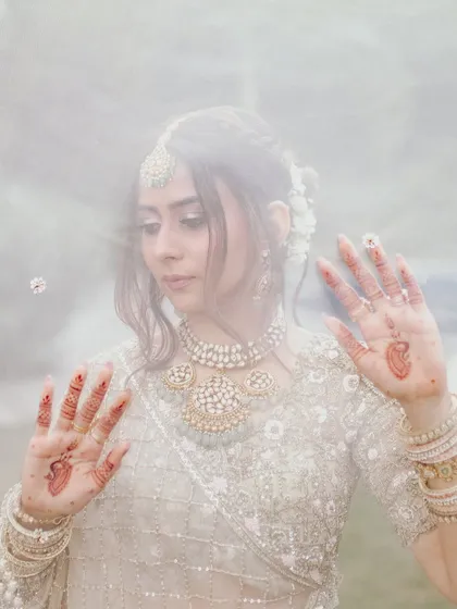 An artistic shot of the bride through her veil, showcasing her delicate henna and soft, dreamy eye makeup. This style of photography beautifully captures the ethereal quality of the look.