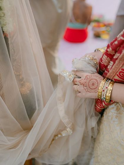 A beautiful detail shot capturing the bride's henna, bangles, and the texture of her traditional saree.