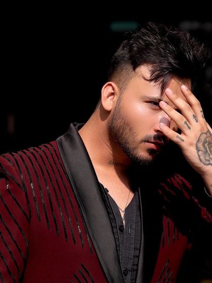 A client in a striking maroon tuxedo jacket with black sequin stripes. This is a bold, fashion-forward piece for someone who isn't afraid to stand out.