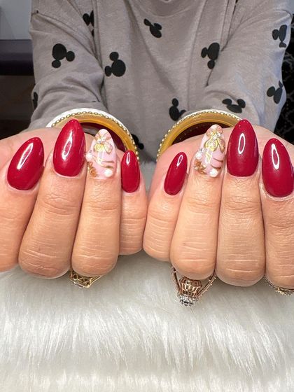 The full set of red nails with intricate gold and pearl floral accents.