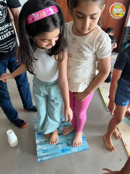 Teamwork makes the dream work. Two kids carefully balance on the paper cup platform, learning about collaboration and structural integrity together.
