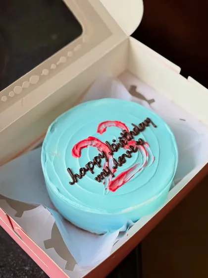 A close-up of the blue minimal bento cake, showing the texture of the buttercream and the hand-piped message.