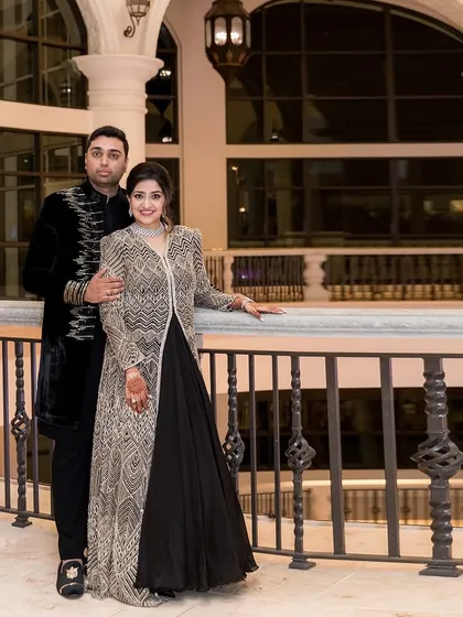 A classic portrait from a monochrome-themed reception. The groom's black velvet Manish Malhotra sherwani and the bride's embellished Ritika Mirchandani jacket create a look of pure opulence.