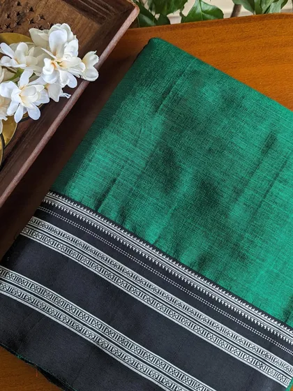 A classic bottle green Ilkal saree with a black and silver border. This is an elegant and timeless choice for any occasion.