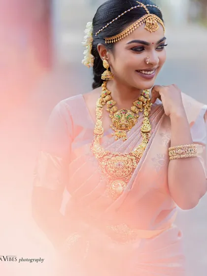 A dreamy, soft-focus shot of a model in a traditional muhurtham look. The peachy tones and dewy finish give a very ethereal feel.