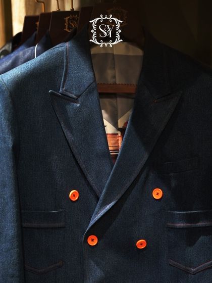 This double-breasted denim blazer with bright orange buttons is a perfect example of a modern, statement-making piece. It combines a classic silhouette with a playful, contemporary twist.