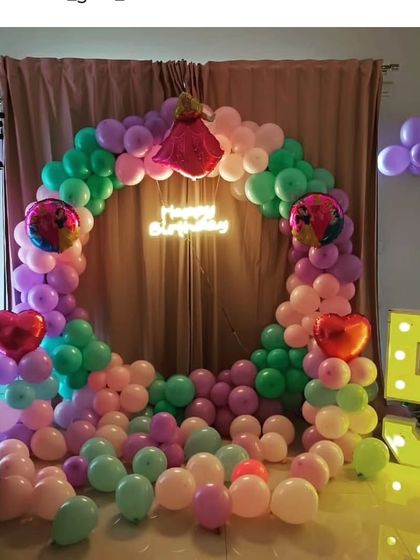 A colorful circular balloon ring with a doll and a large light-up number "5".