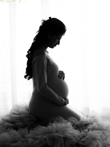 A serene and beautiful silhouette portrait of a mom-to-be. The soft light and the texture of the ruffled gown create a stunning monochrome image.