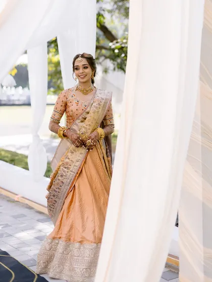 Bathed in blessings and glowing with happiness. This bride looks stunning for her Haldi ceremony in a peach and gold half saree, her makeup kept fresh and radiant.