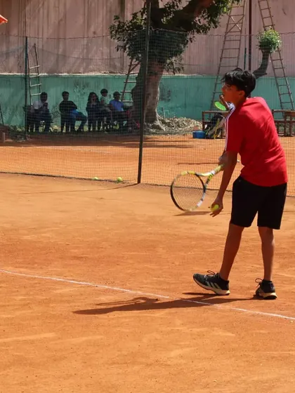 A young player preparing to serve, showing the focus we teach from an early age.