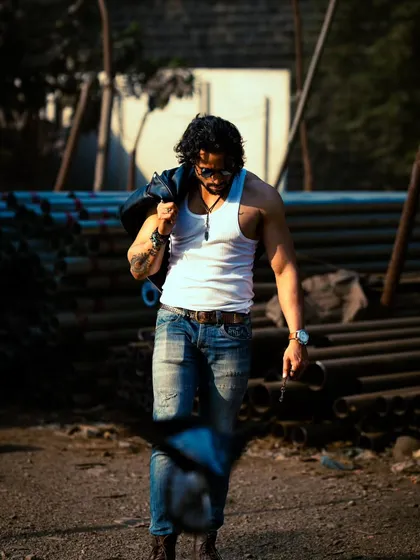 A powerful walking shot, with the jacket slung over the shoulder. The high-contrast lighting emphasizes muscle definition and a confident stride.