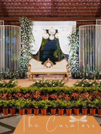 A wider perspective of the reception stage, showing the row of potted plants that adds a touch of natural greenery and color to the sophisticated setup.