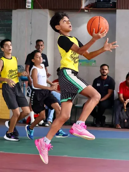 A player goes up for a layup in mid-air during a competitive match. This action shot captures the athleticism and skill we nurture at the academy.
