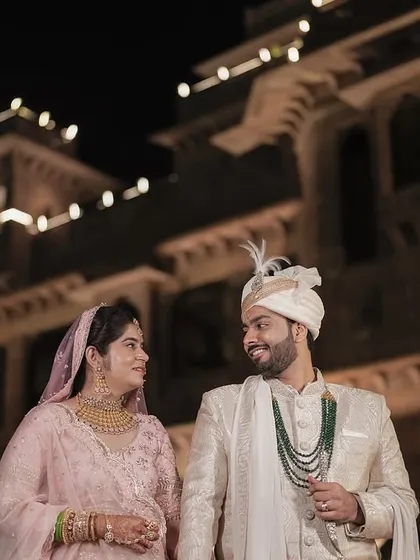A night portrait of the couple against the illuminated facade of the Radisson Jodhpur, creating a royal and grand feel.