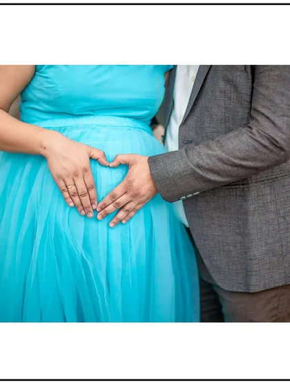 A classic heart-hands pose over the baby bump, a timeless symbol of love and family.