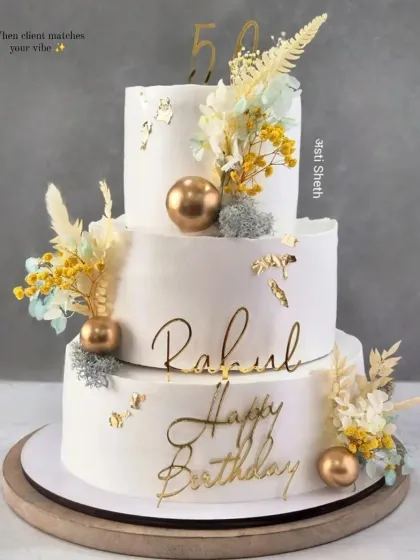 A magnificent three-tiered cake for a 50th birthday. This 6kg Cherry Chocolate cake features dried florals, gold accents, and elegant script.