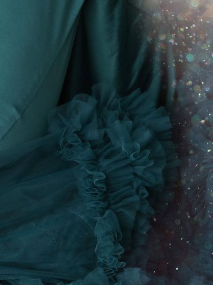 A macro detail shot capturing the sparkle and texture of a teal tulle gown, showing the quality and beauty of the outfits available in my studio.