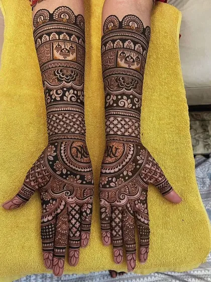 A beautiful example of a full bridal set with matching designs on both hands. The pattern includes personalized initials 'N' and 'V' inside decorative circles on the palms.