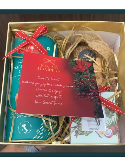 A peek inside a cozy Secret Santa hamper for the holiday season. It features Italian cookies, gourmet snacks, and a personalized note to spread festive cheer.