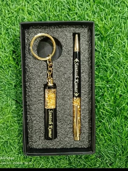 A matching set of a personalized gold-flaked pen and keychain, both engraved with the name 'Santosh Kumar'.